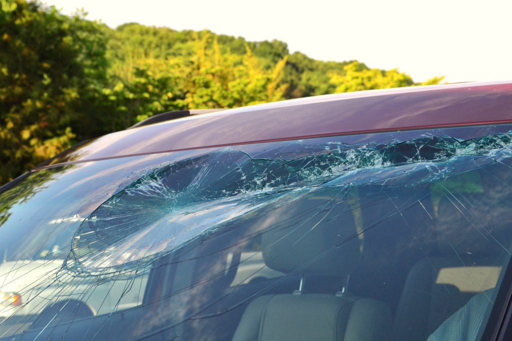 Damage to a vehicle windshield after an accident where it was hit by flying debris on the highway.